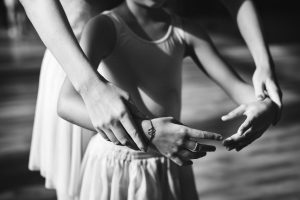 Closeup of young ballerina practice ballet with teacher grayscal